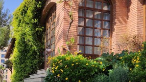 A brick building with arched windows and a garden with daisies. - Parador de Calahorra (Calahorra)