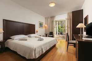 A hotel room with a large bed, a desk, a chair, and a balcony with curtains. - Hotel Croatia (Baska Voda)