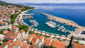 Une ville côtière dotée d’un port de plaisance, de bâtiments aux toits recouverts de tuiles rouges et offrant une vue dégagée sur la mer.