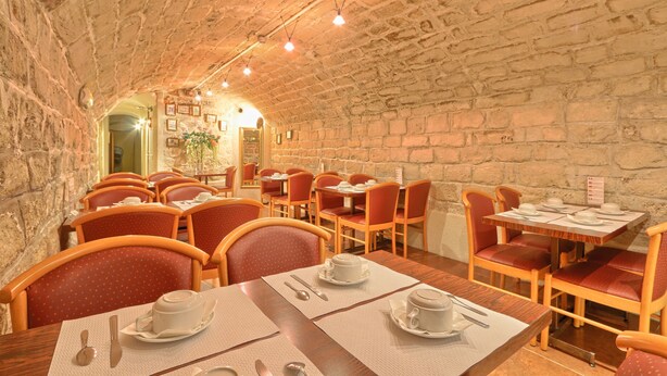 A restaurant with stone walls, wooden tables, and red upholstered chairs. - 121 Paris Hotel (Paris)