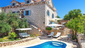 A stone villa with a swimming pool, outdoor seating, and a staircase leading to the upper floors. - Villa Vicina (Milna)