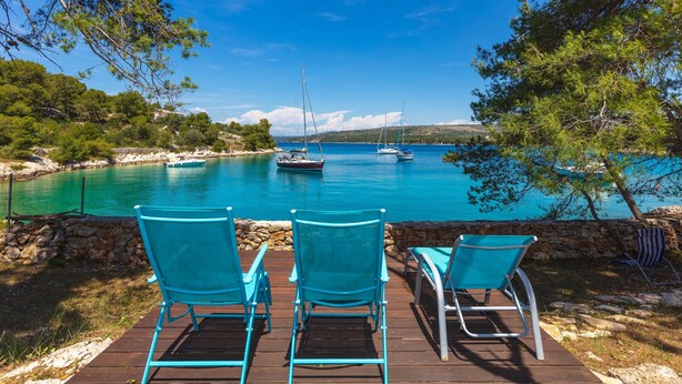A wooden deck with three turquoise chairs facing a calm sea with boats. - Villa Vicina (Milna)