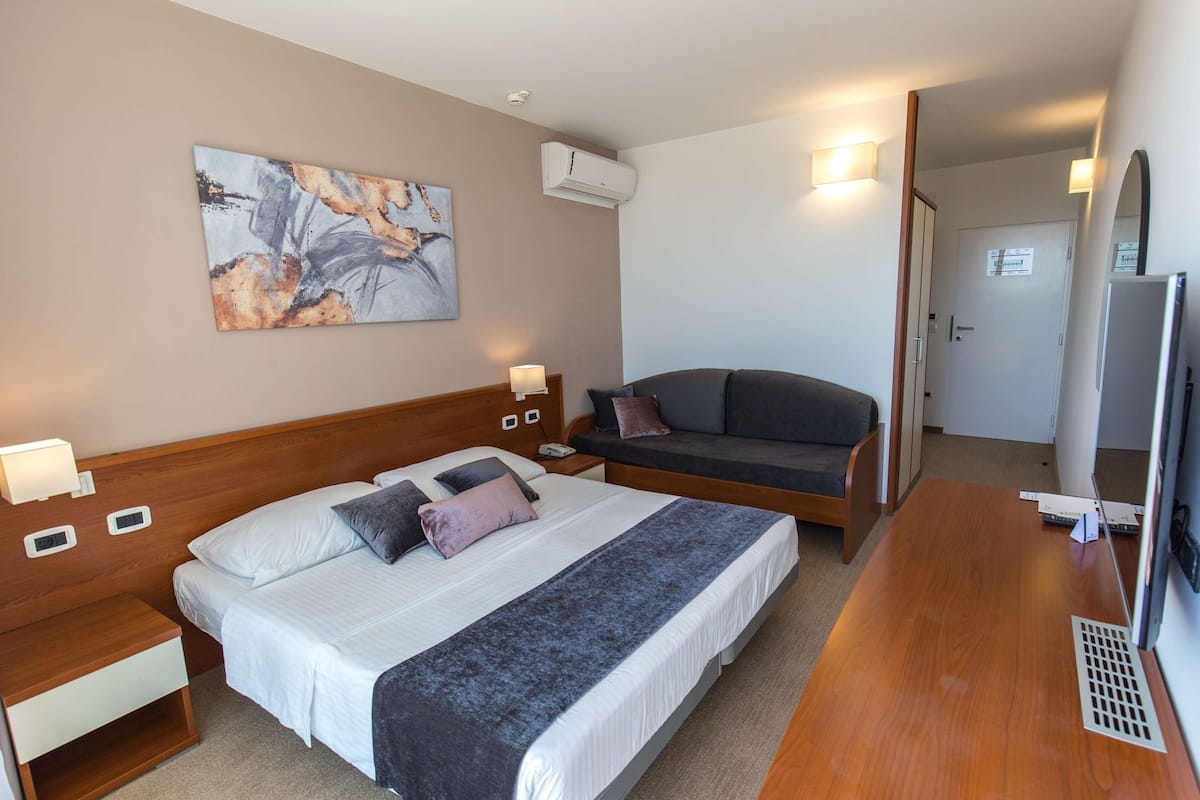 Une chambre d’hôtel équipée d’un lit, de tables de chevet, d’un canapé, d’une télévision et d’un appareil de climatisation.