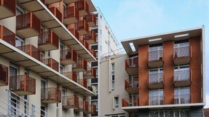 Un immeuble résidentiel à plusieurs étages, doté de balcons, d’un escalier et d’un toit plat.