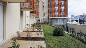 Un immeuble d’appartements moderne doté de balcons, d’un petit jardin et d’un chemin piétonnier dallé.