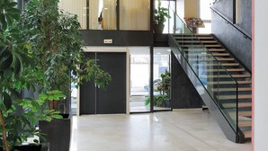 Un hall d’entrée spacieux, agrémenté d’un escalier, de plantes en pot et d’un design moderne au plafond.