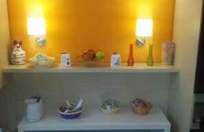 A hotel reception area with a counter displaying various items like a basket, a vase, and a fruit bowl. - San Lorenzo Guest House (Rome)