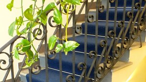 A staircase with ornate black metal railings and blue steps. - San Lorenzo Guest House (Rome)