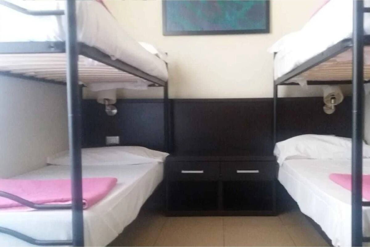 A bunk bed room with two beds, a small storage unit, and a painting on the wall.