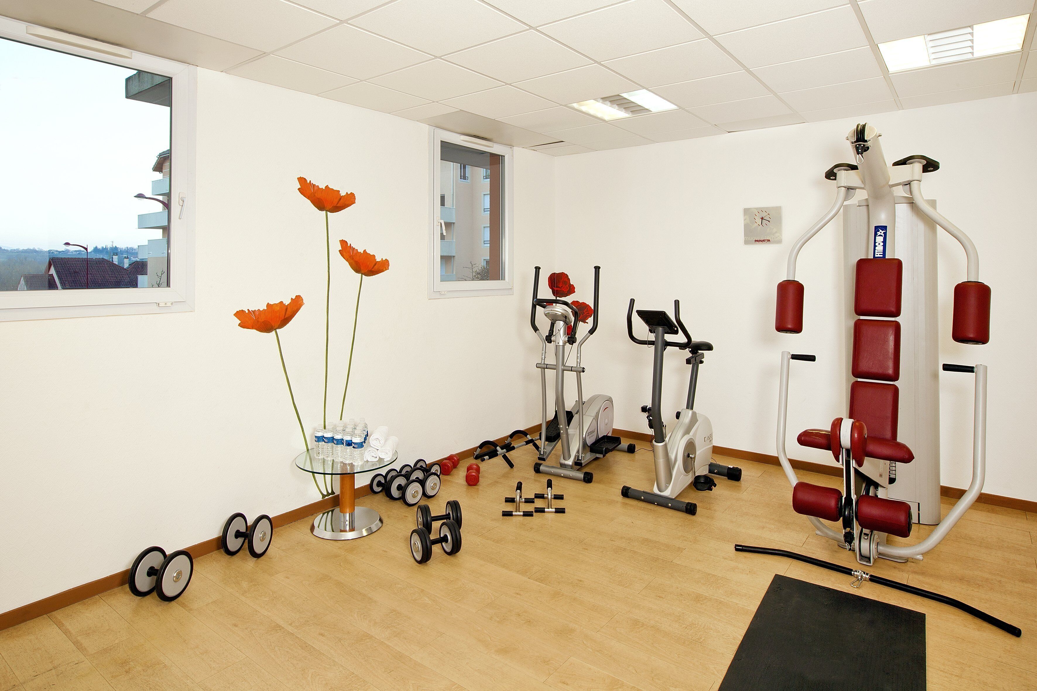 A gym with exercise equipment, a window, and a view of buildings outside.