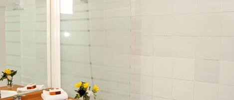 A modern bathroom with a glass shower enclosure, a wooden vanity, and a large mirror.
