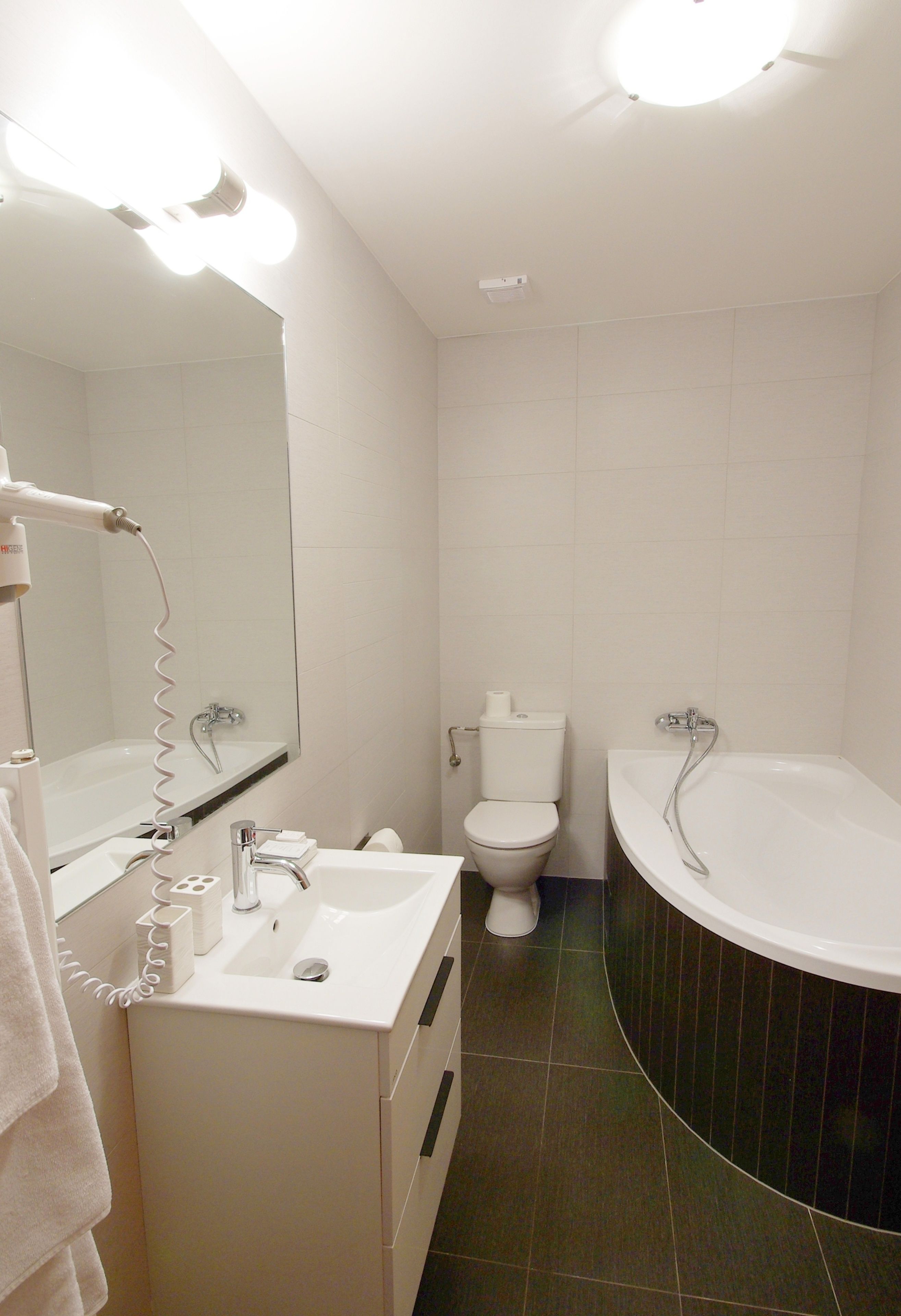 Un baño con lavabo, espejo, inodoro y bañera.