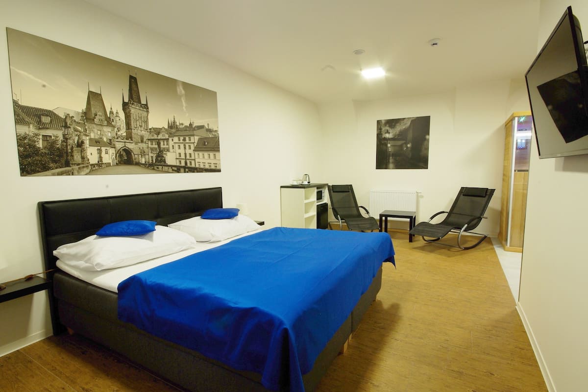Una camera d'albergo con un letto, una scrivania, una sedia e una televisione appesa al muro.