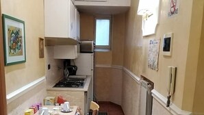 Una cocina compacta con estufa a gas, una mesa pequeña con sillas y una ventana.