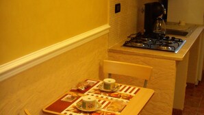 Cocina compacta con una mesa de comedor lista para dos personas, estufa a gas y una pequeña encimera.