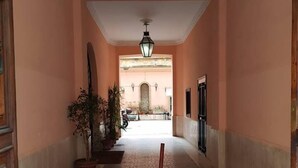Un pasillo con suelo de baldosas, un farol colgante y plantas en macetas.