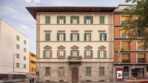 A multi-story building with a classic architectural style, featuring a central entrance with a large wooden door and green shutters on the windows. - B&B Il Marzocco (Florence)