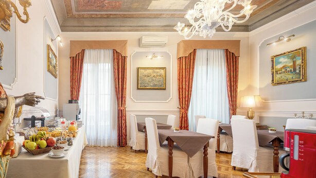 A dining area with a table set for four, a red coffee machine, and a buffet with fruits and pastries. - B&B Il Marzocco (Florence)