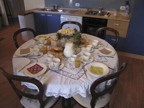 A round dining table set with plates, bowls, and cups, surrounded by chairs. - Marci's Home (Rome)