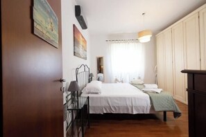 A bedroom with a bed, a bedside table, a lamp, a wardrobe, and a window with curtains. - Marci's Home (Rome)