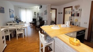 A modern kitchen with a wooden countertop, white chairs, and a dining table. - Marci's Home (Rome)