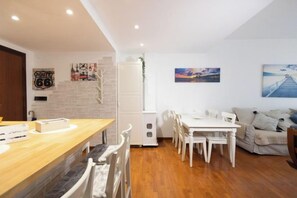 Ein modernes Wohnzimmer mit einem Holzespeisetisch und Stühlen, einem weißen Sofa und einem weißen Schrank.