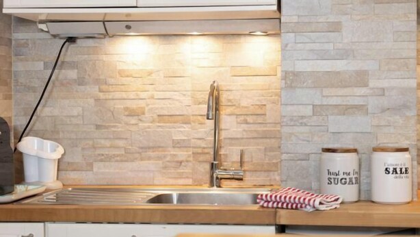 A kitchen with a stone backsplash, a stainless steel sink, and two jars labeled "Hustle me in Sugar" and "Sale della vita". - Marci's Home (Rome)