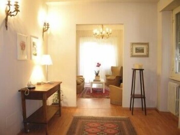 A cozy living room with a wooden floor, a sofa, a coffee table, and a chandelier. - Marci's Home (Rome)