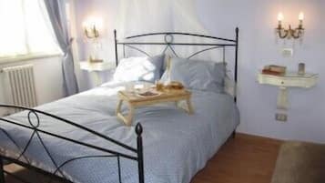 Un letto rifatto con cura, un comodino e una mensola a parete con una lampada.