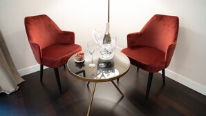 A room with two red velvet chairs around a small round table with a bottle and glasses. - Kame Hall (Rome)