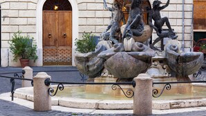 A stone fountain with sculptures of sea creatures and a wooden door in the background. - Kame Hall (Rome)