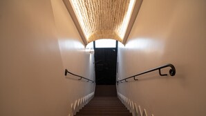 A staircase with wooden steps and metal handrails, leading to a dark door at the top. - Kame Hall (Rome)