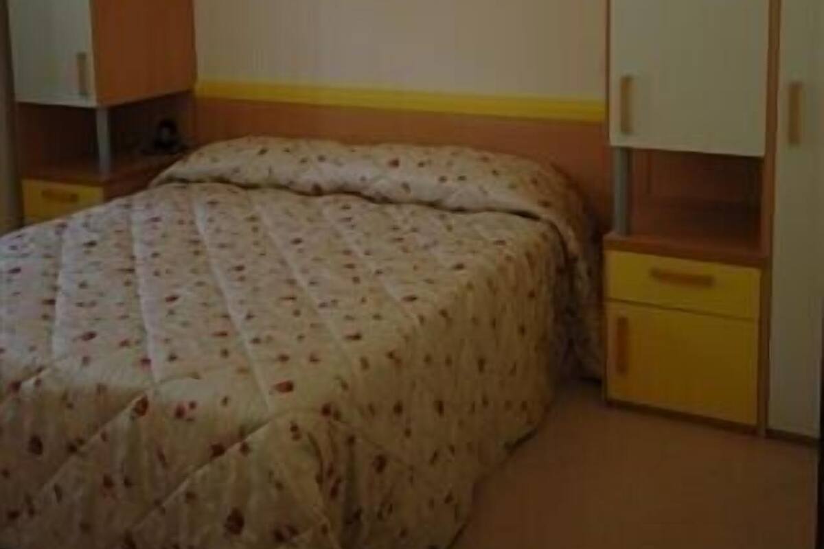Ein Schlafzimmer mit Bett, Kleiderschrank und Regalelement.