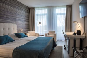A hotel room with a large bed, two chairs, a desk, and a TV. - Hotel Molenbos (De Cocksdorp)