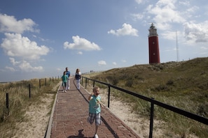 A brick pathway leading to a red lighthouse. - Hotel Molenbos (De Cocksdorp)