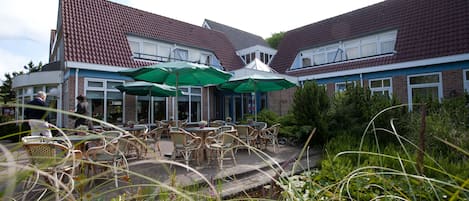 A courtyard with outdoor seating, a small pond, and a building with a tiled roof.