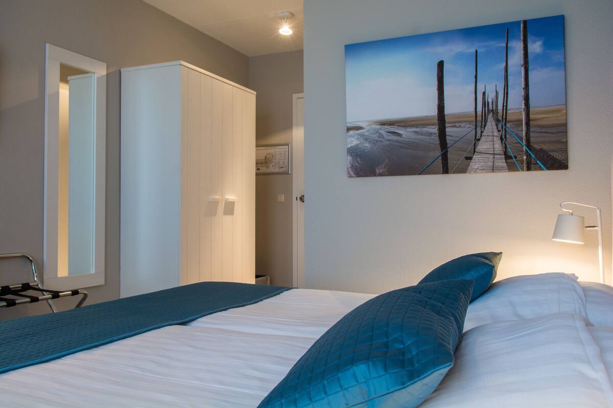 Ein Schlafzimmer mit einem Bett, einem Kleiderschrank, einem Bild eines Piers und einer Lampe.