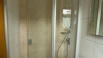 A modern bathroom with a glass-enclosed shower, a white sink, and a mirror above it.