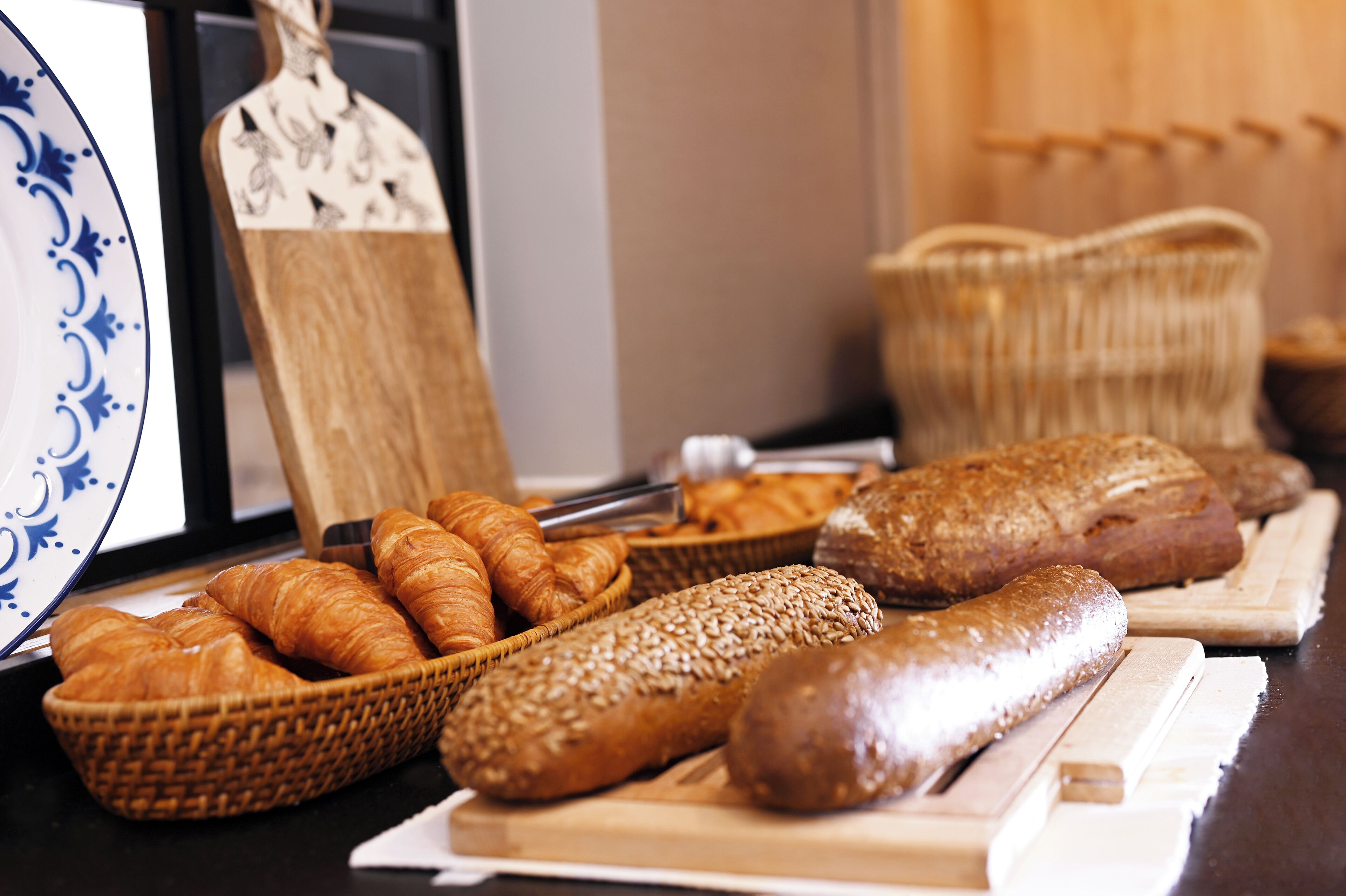 Diverse broden en gebak op een toonbank, waaronder croissants, een stokbrood en een brood met sesamzaadjes.