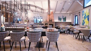 Un restaurant moderne doté de hauts plafonds, d’un éclairage suspendu et de différents types de mobilier, notamment des chaises et des tables aux motifs variés.