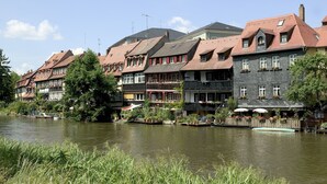 Un hôtel situé au bord de la rivière, doté d’une architecture traditionnelle, de plusieurs étages, de balcons ornés de plantes et d’une rangée de bateaux amarrés le long du quai.