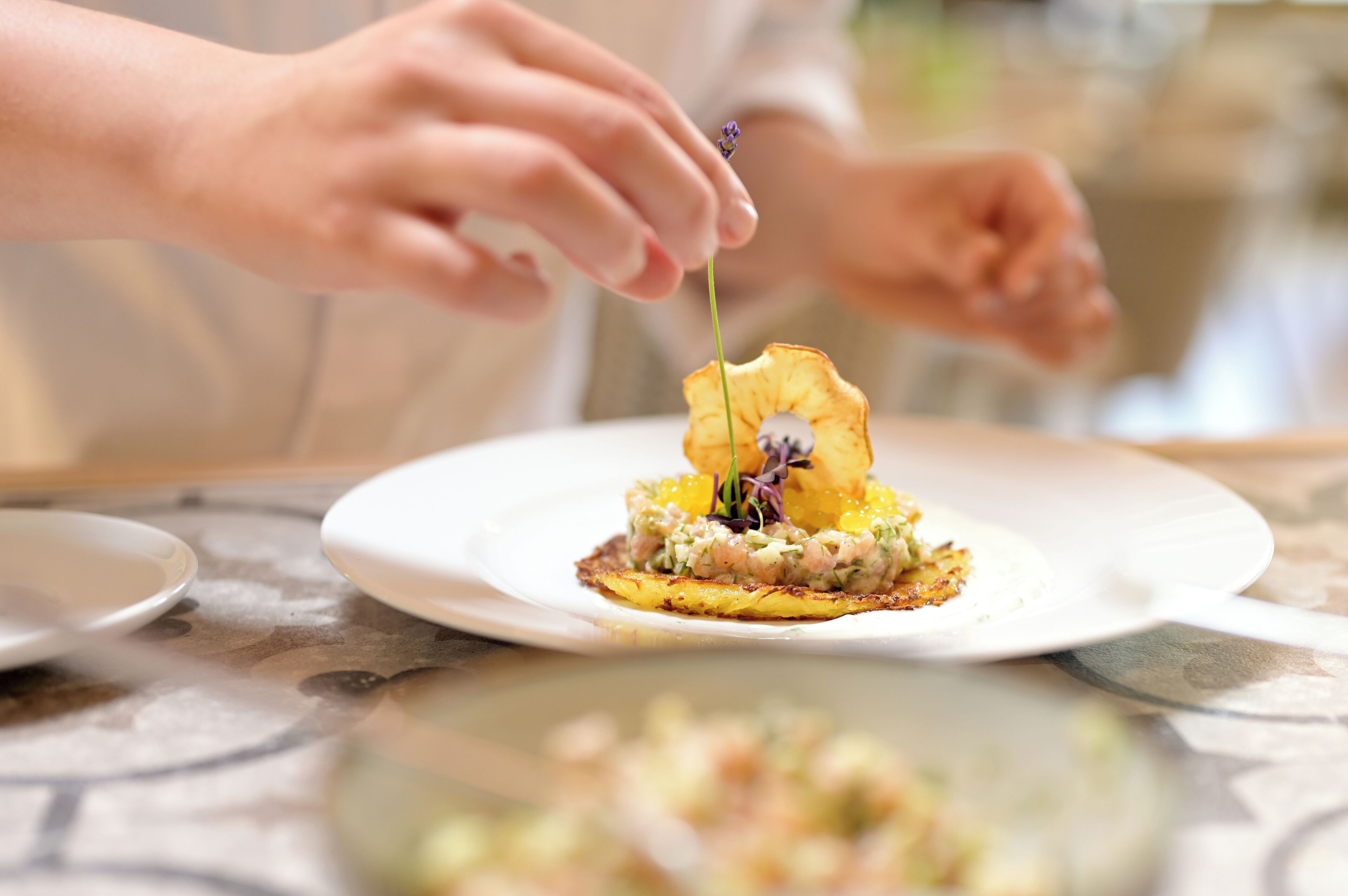 A person placing a flower on a dish of food.