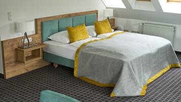 A neatly arranged hotel room with a bed, a nightstand, a lamp, and a window with skylights.