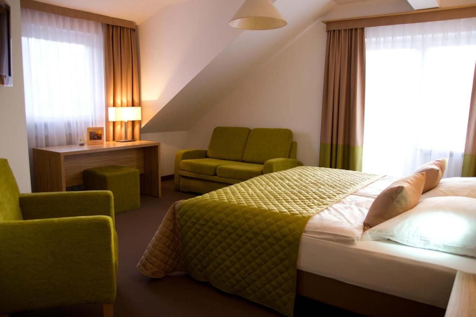 Quarto de hotel com cama, escrivaninha, cadeira e abajur.