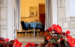 An open doorway leading to a dining area with a table set for two, chairs, and a kitchen visible in the background. - Villa PaPe (Trogir)