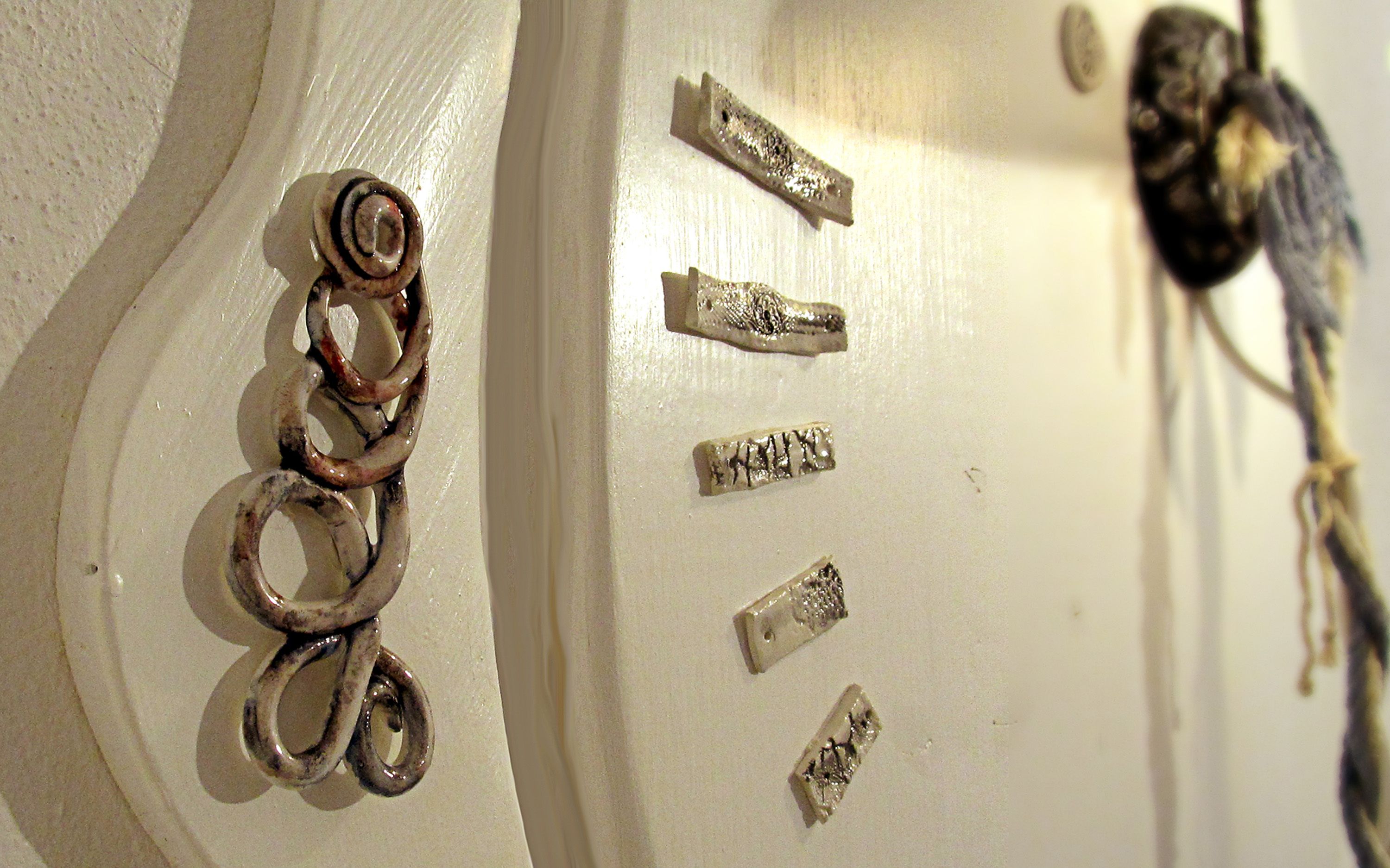 A close-up of a white door with a spiral handle, a brass doorknob, and several small, rectangular metal pieces with inscriptions.