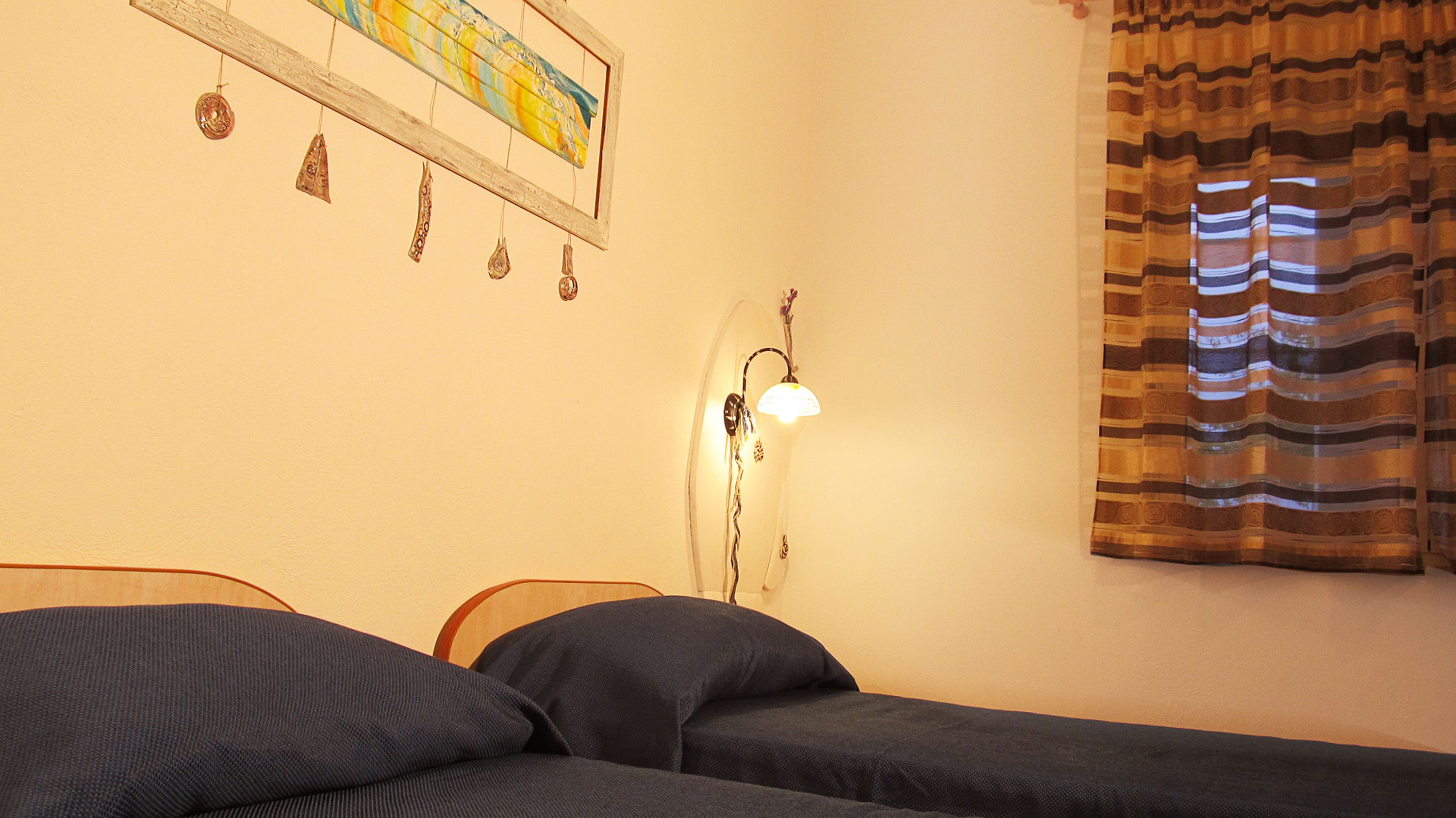 Une chambre à coucher avec un lit, une lampe fixée au mur et un rideau.