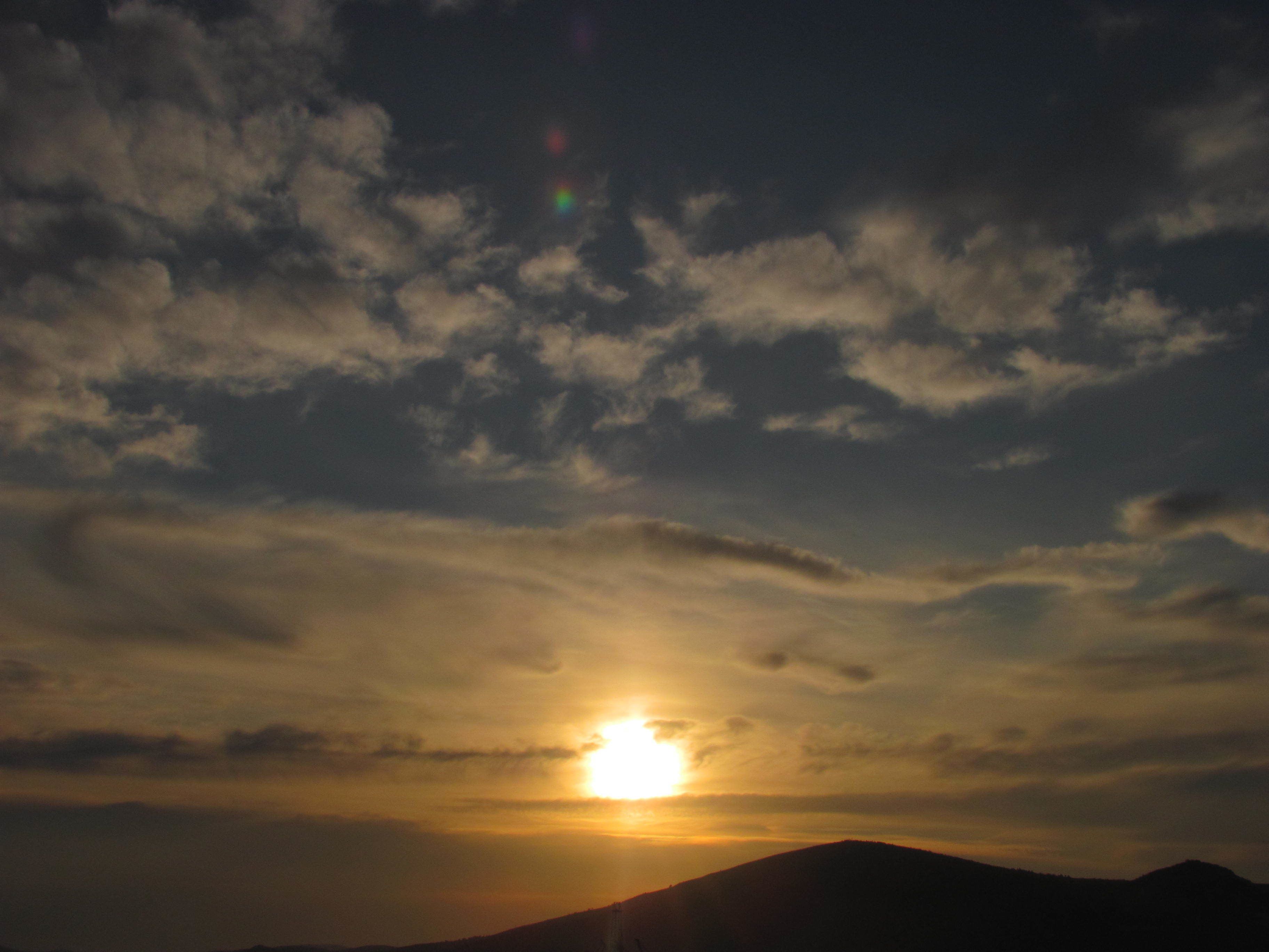 A sunset over a mountain range with clouds in the sky.