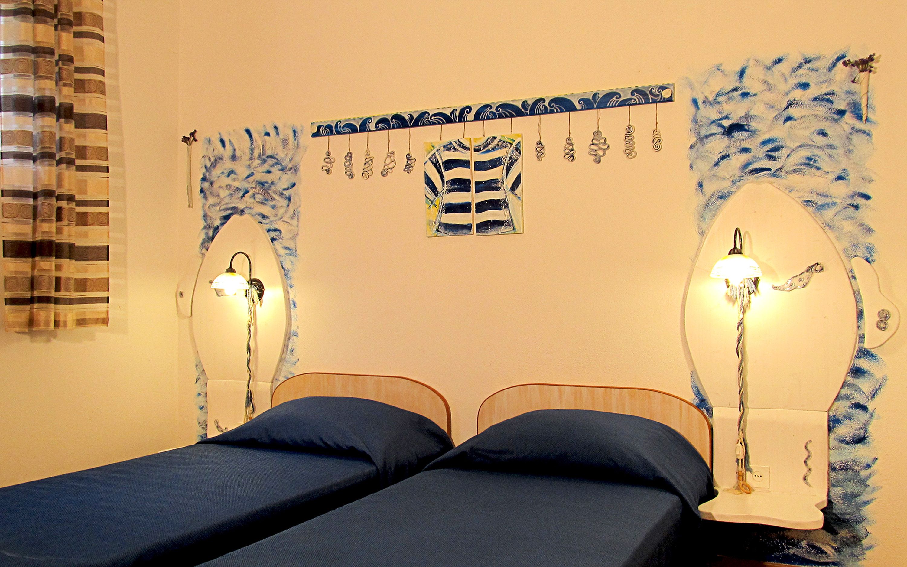 A room with two beds, a wall-mounted light fixture, and a decorative item above the beds.
