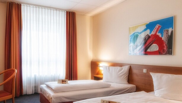 A hotel room with two beds, a desk with a television, and a painting on the wall. - Center Hotel Drive Inn (Hirschaid)